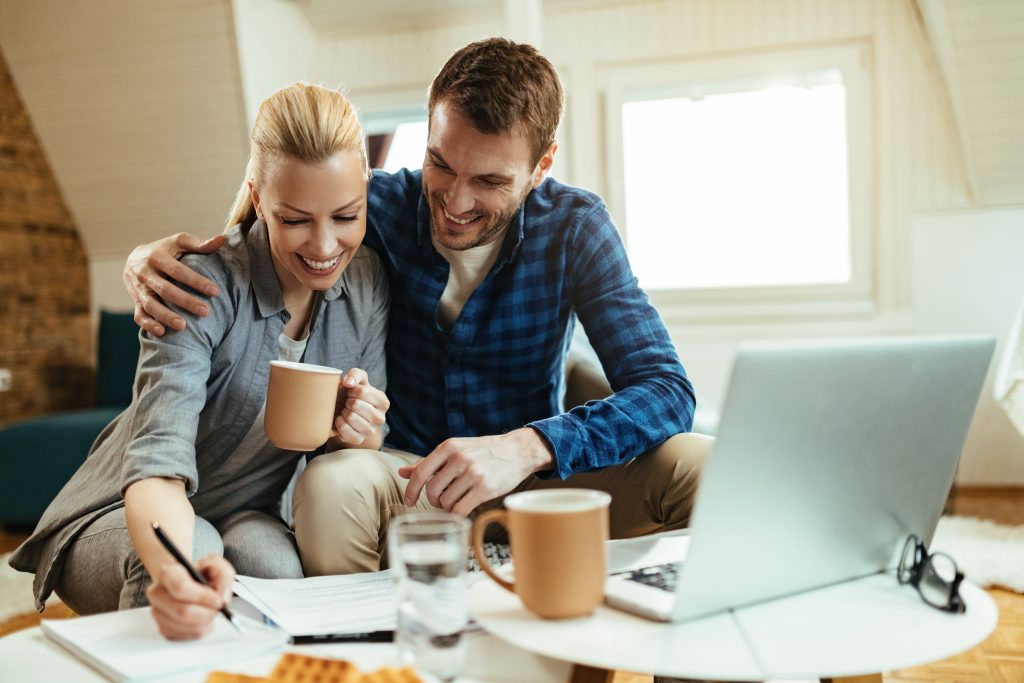 Un couple échange autour de son budget et prend des notes à la maison.