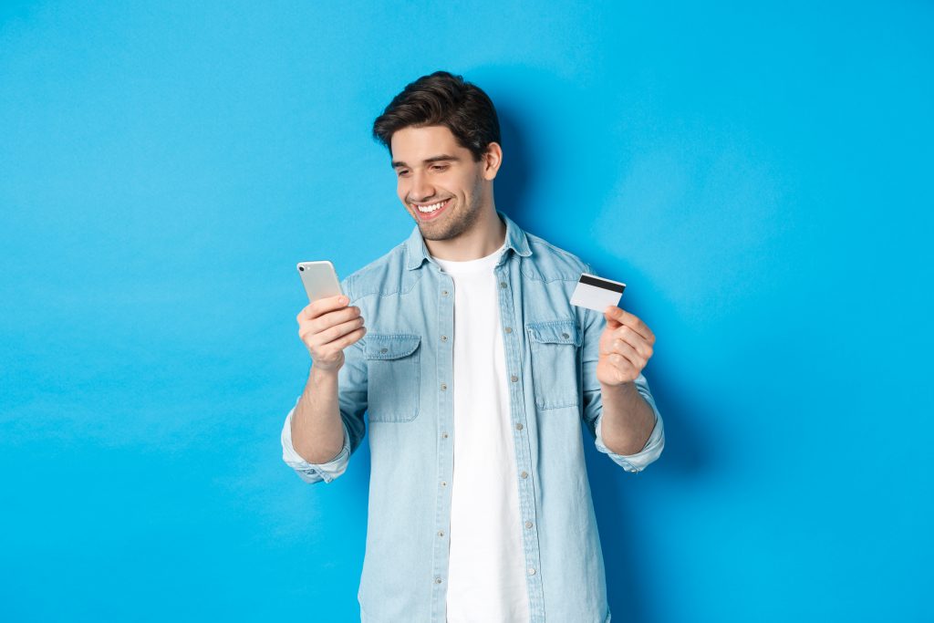 Un homme utilise un téléphone et tient une carte bancaire.