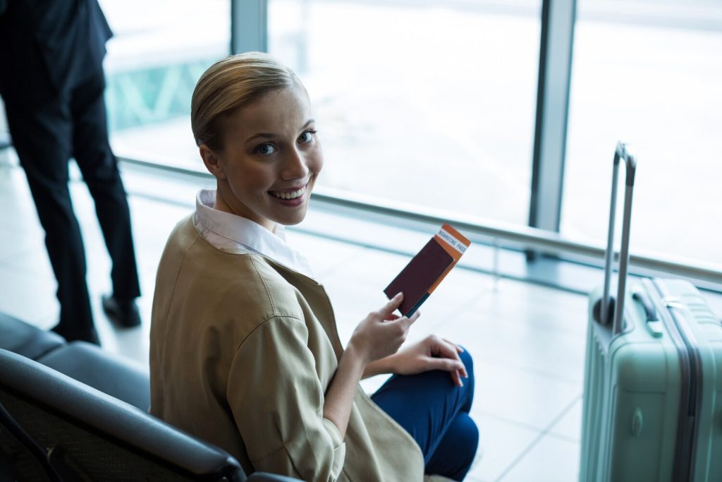 portrait of female commuter with passport and boarding pass in waiting area