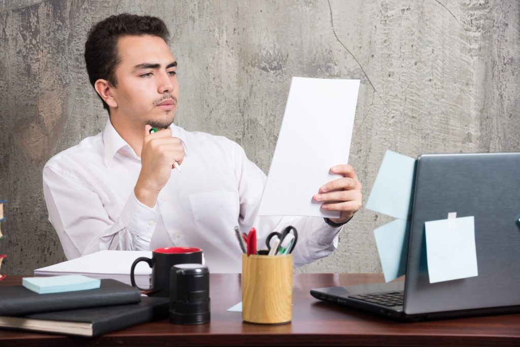 young businessman looking work papers at the office desk.
