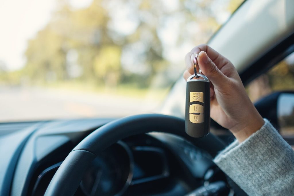 A woman holding and showing car key while sitting in the car