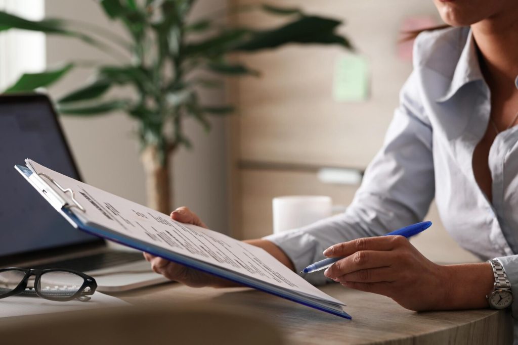 unrecognizable female entrepreneur analyzing business reports while working on paperwork in the office