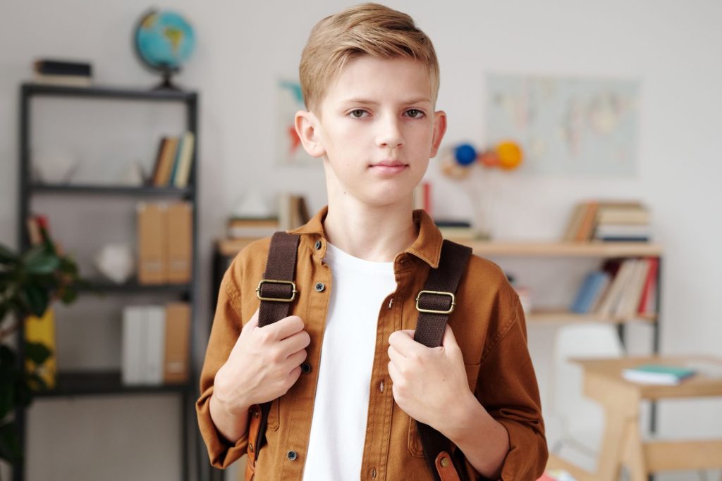 Un élève avec son cartable dans une salle de classe.